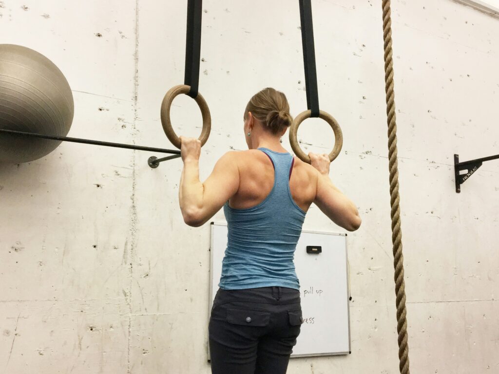 a woman doing a ring pull up 